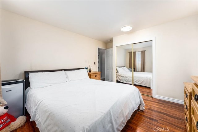 bedroom featuring baseboards, dark wood finished floors, and a closet