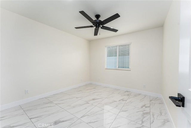 empty room featuring a ceiling fan, marble finish floor, and baseboards