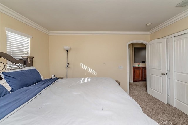 carpeted bedroom with ornamental molding and a closet