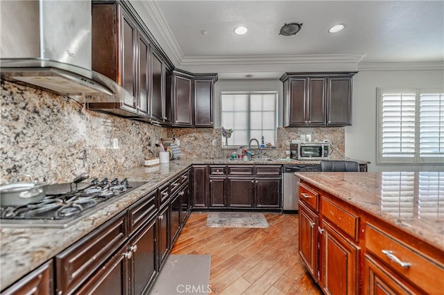 kitchen with stainless steel appliances, wall chimney range hood, crown molding, and light stone countertops