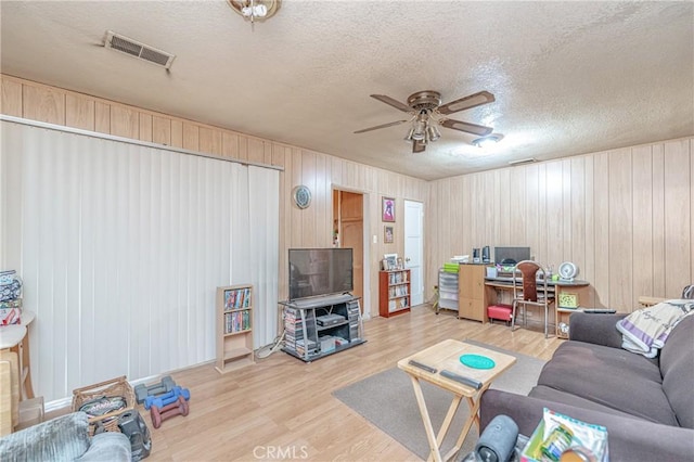 living room with ceiling fan, wood-type flooring, and a textured ceiling