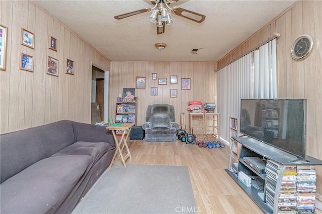 living room featuring ceiling fan, a textured ceiling, and light hardwood / wood-style floors