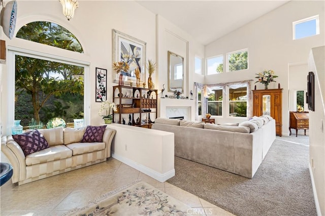 carpeted living room with high vaulted ceiling and an inviting chandelier