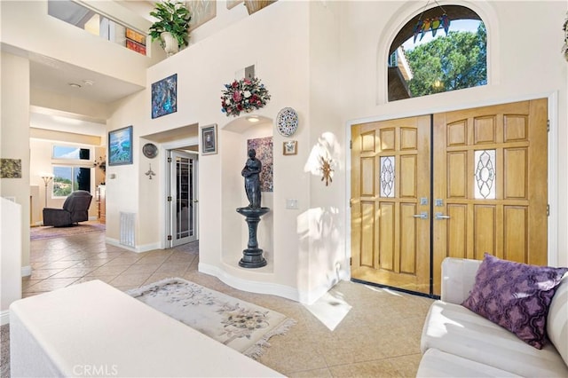 foyer featuring a high ceiling, light tile patterned floors, and plenty of natural light