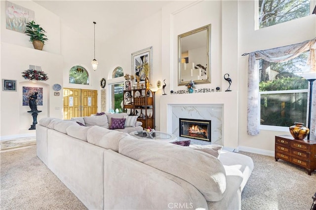 carpeted living room with a towering ceiling and a high end fireplace