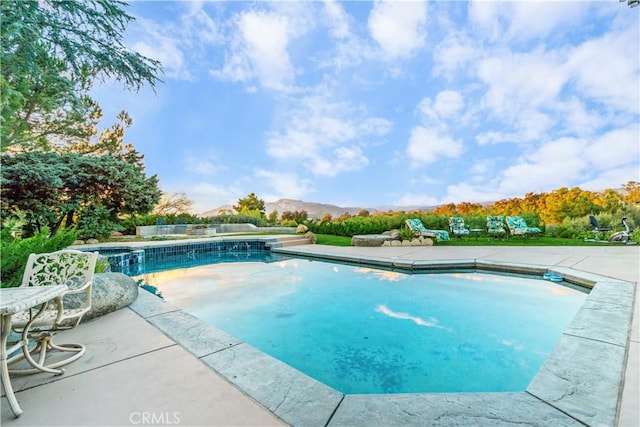 view of pool featuring a patio area, a mountain view, and an in ground hot tub