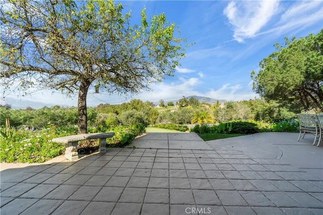 surrounding community with a mountain view and a patio