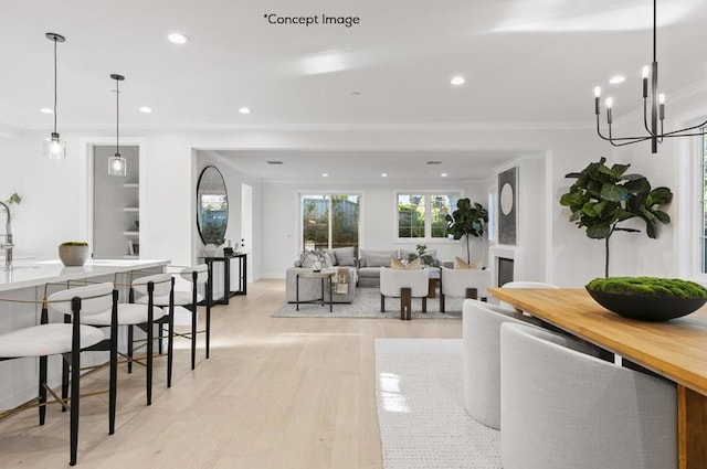 dining room featuring sink, light wood-type flooring, crown molding, and a notable chandelier