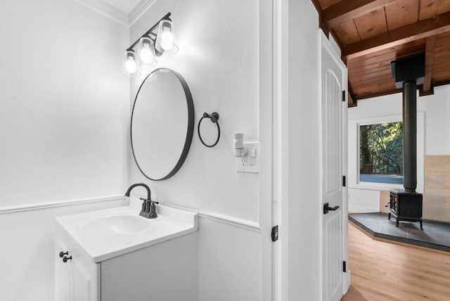 bathroom featuring crown molding, wood-type flooring, wooden ceiling, a wood stove, and vanity