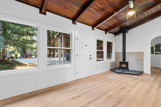 unfurnished sunroom with vaulted ceiling with beams, wood ceiling, ceiling fan, and a wood stove