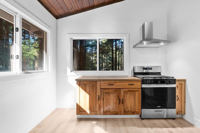 kitchen with wood ceiling, stainless steel range with gas stovetop, light hardwood / wood-style floors, vaulted ceiling, and wall chimney exhaust hood