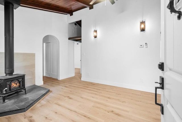 living room featuring wood ceiling, light hardwood / wood-style flooring, a wood stove, ceiling fan, and beam ceiling