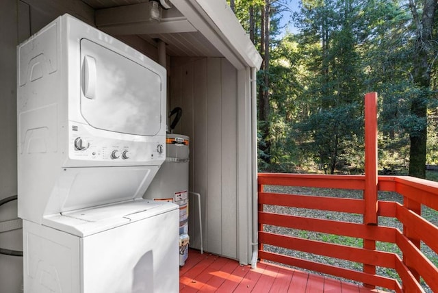 laundry area with water heater, stacked washer / drying machine, and light hardwood / wood-style flooring