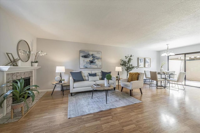 living room featuring hardwood / wood-style flooring, a notable chandelier, a textured ceiling, and a fireplace