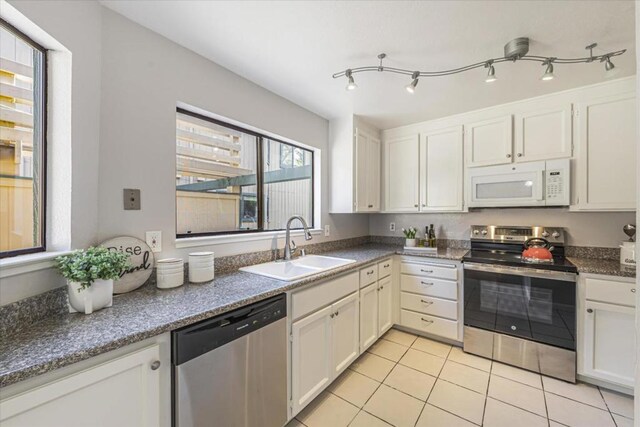 kitchen with white cabinetry, sink, light tile patterned floors, and stainless steel appliances