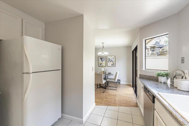 kitchen featuring light tile patterned floors, sink, white cabinetry, white refrigerator, and stainless steel dishwasher