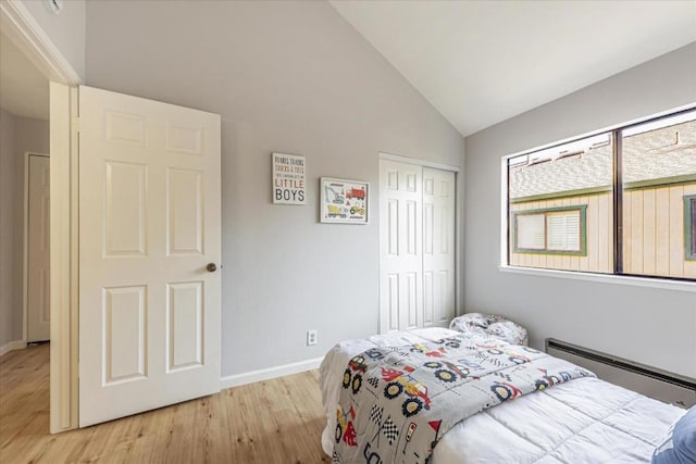 bedroom featuring a baseboard radiator, high vaulted ceiling, a closet, and light wood-type flooring