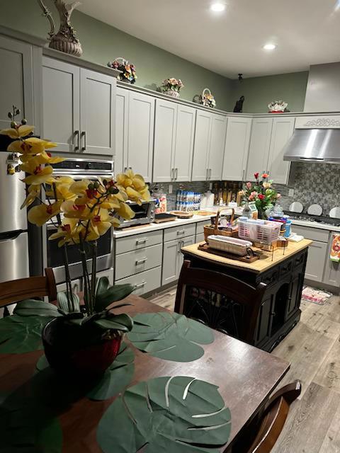 kitchen with light wood-type flooring, appliances with stainless steel finishes, and tasteful backsplash