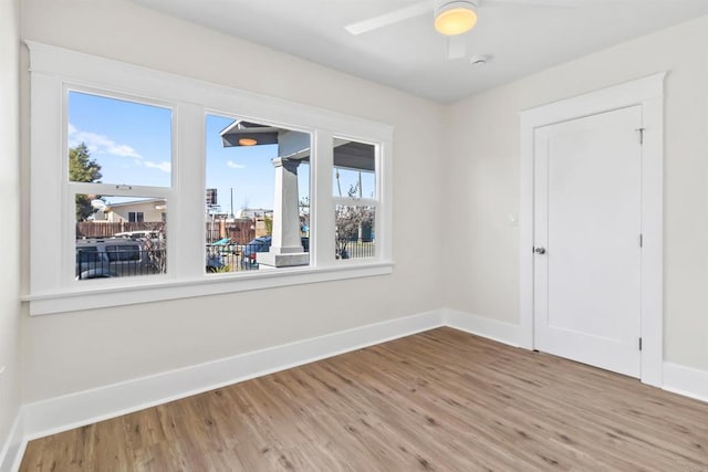 unfurnished room featuring a healthy amount of sunlight, ceiling fan, and hardwood / wood-style flooring