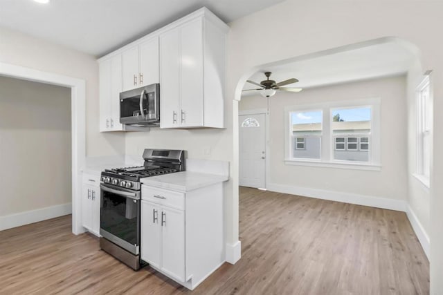 kitchen with stainless steel appliances, light wood-type flooring, ceiling fan, and white cabinets