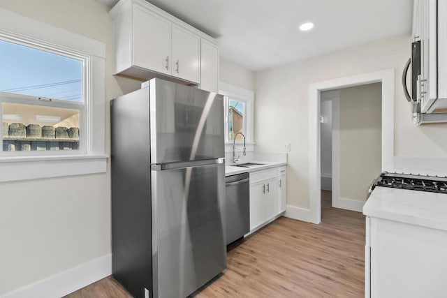 kitchen featuring white cabinets, light wood-type flooring, appliances with stainless steel finishes, and sink