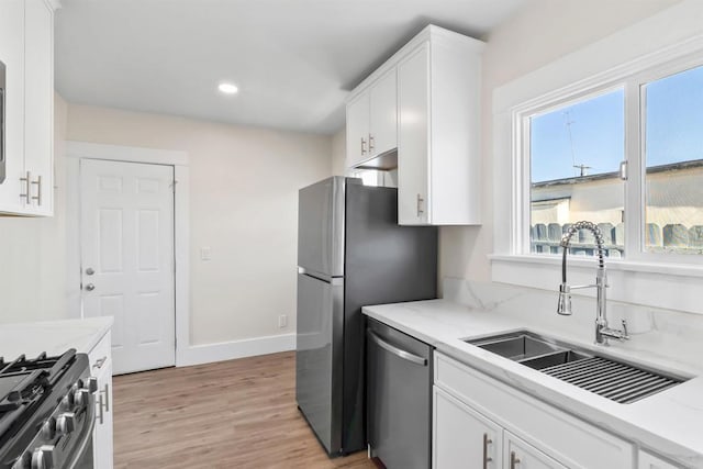 kitchen featuring sink, white cabinets, light hardwood / wood-style flooring, light stone countertops, and appliances with stainless steel finishes