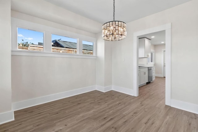 unfurnished dining area with hardwood / wood-style floors, a chandelier, and a healthy amount of sunlight