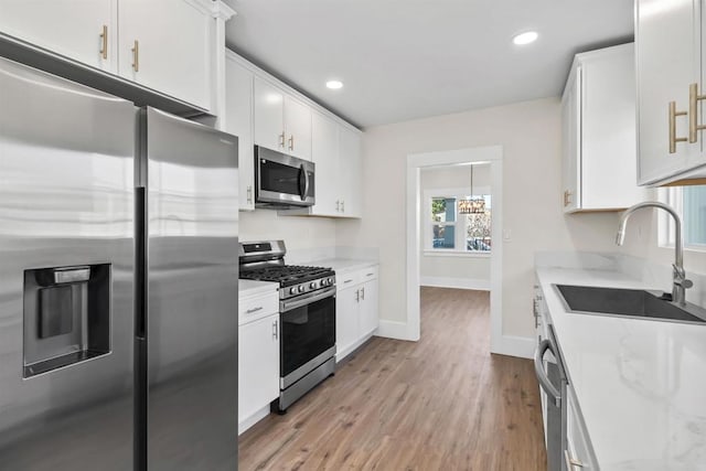 kitchen featuring sink, stainless steel appliances, light stone counters, and white cabinetry