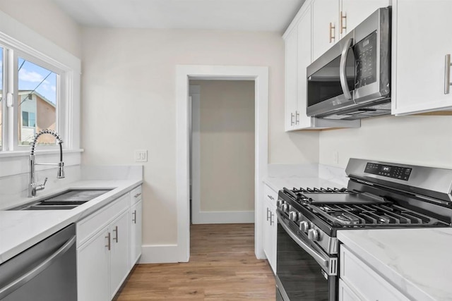 kitchen with sink, stainless steel appliances, light hardwood / wood-style floors, and white cabinets