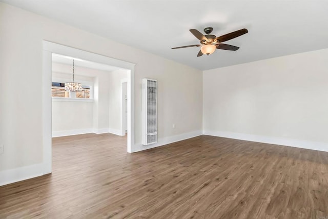 empty room with dark wood-type flooring and ceiling fan with notable chandelier