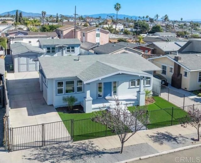 view of front of home featuring a fenced front yard, concrete driveway, a front yard, a mountain view, and a residential view