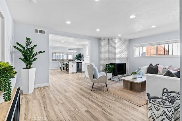 living room featuring a fireplace, light hardwood / wood-style floors, and wine cooler