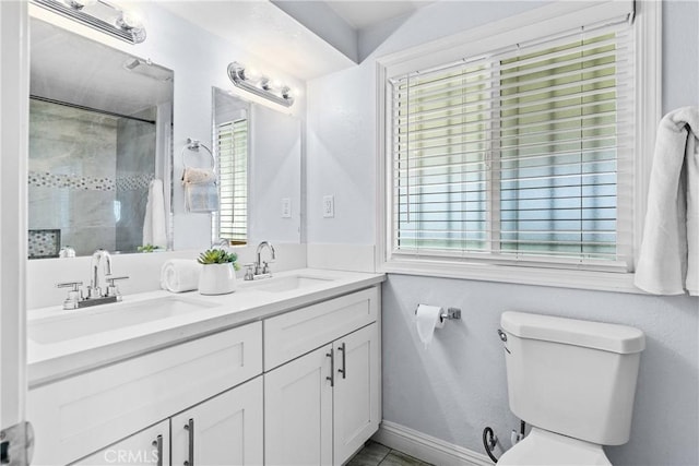 bathroom featuring a tile shower, vanity, toilet, and a wealth of natural light