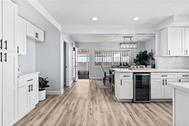 kitchen with tasteful backsplash, wine cooler, white cabinetry, and decorative light fixtures