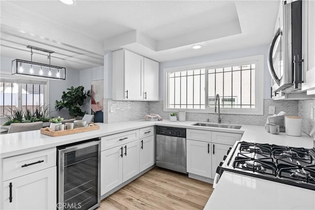 kitchen with appliances with stainless steel finishes, white cabinetry, sink, and wine cooler