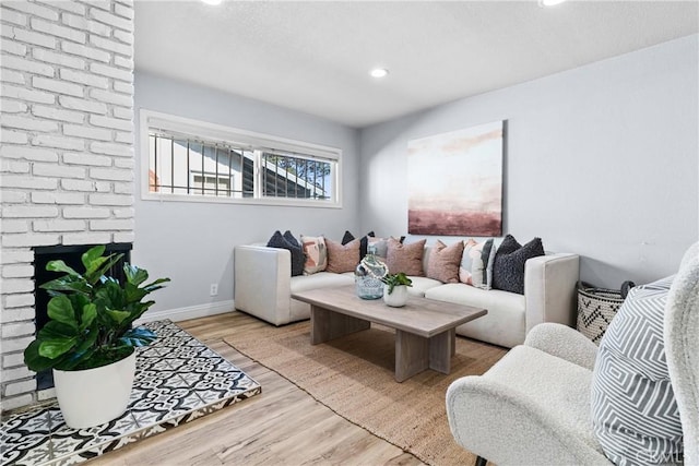 living room featuring light wood-type flooring and a brick fireplace