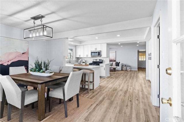 dining area with light hardwood / wood-style floors, a healthy amount of sunlight, and sink