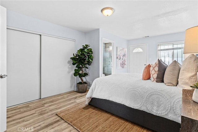 bedroom featuring light hardwood / wood-style flooring, ensuite bath, and a closet