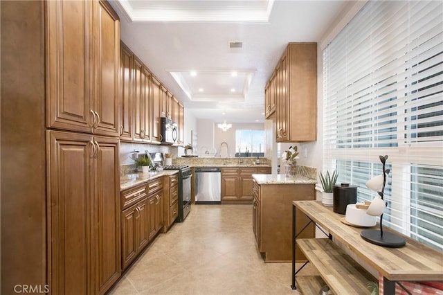 kitchen featuring kitchen peninsula, light stone countertops, stainless steel appliances, and a tray ceiling