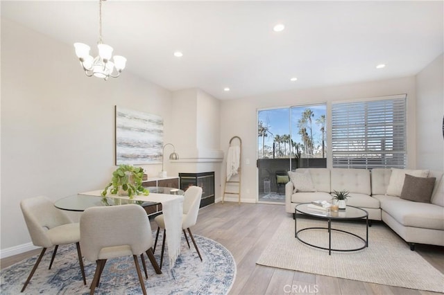 dining space featuring a notable chandelier, a large fireplace, and light hardwood / wood-style flooring