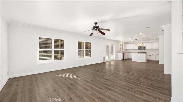 unfurnished living room with crown molding, ceiling fan, and dark wood-type flooring