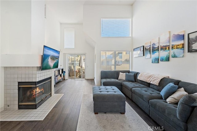 living room featuring a high ceiling, a fireplace, and dark hardwood / wood-style flooring