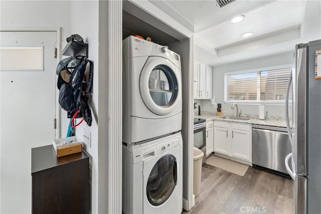 laundry area with stacked washing maching and dryer, dark hardwood / wood-style flooring, and sink