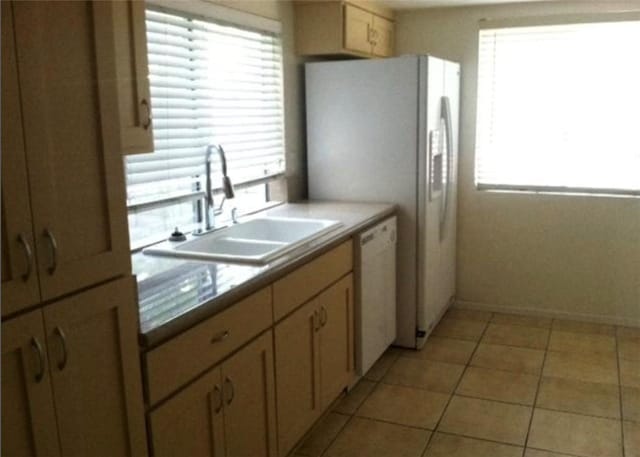 kitchen featuring light tile patterned floors, dishwasher, sink, and light brown cabinets