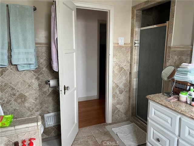 bathroom with a shower with shower door, tile walls, and tile patterned floors