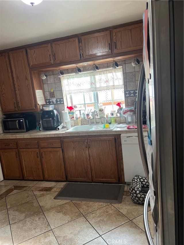 kitchen featuring appliances with stainless steel finishes, sink, tile countertops, and light tile patterned flooring