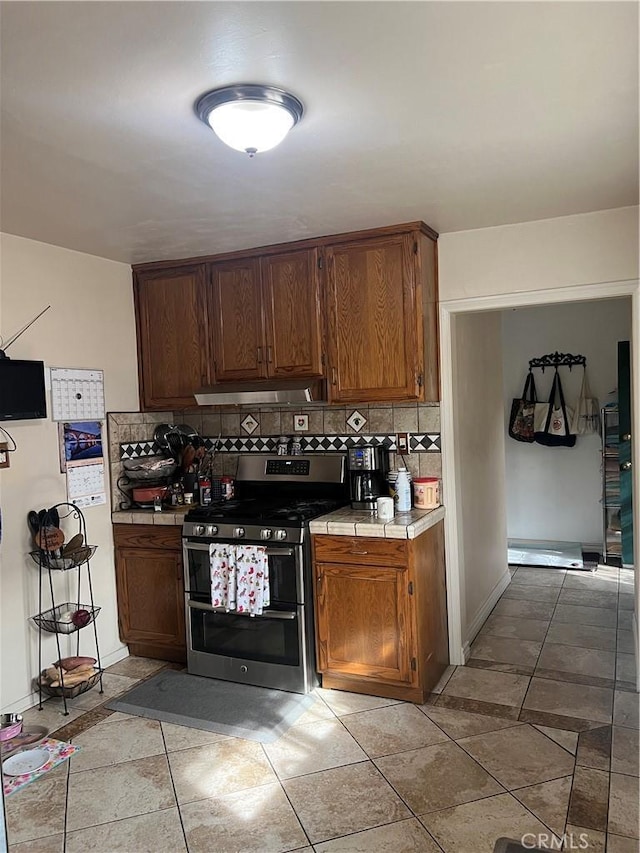 kitchen featuring backsplash, range with two ovens, light tile patterned floors, and tile counters