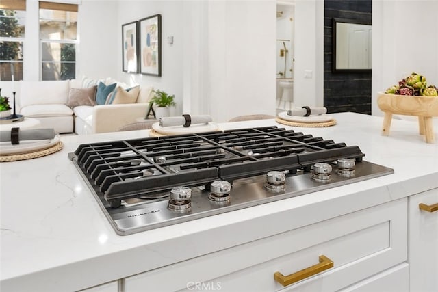 room details featuring white cabinetry, stainless steel gas cooktop, and light stone counters