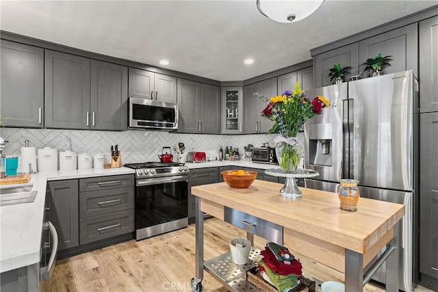 kitchen featuring gray cabinetry, backsplash, light hardwood / wood-style floors, and stainless steel appliances