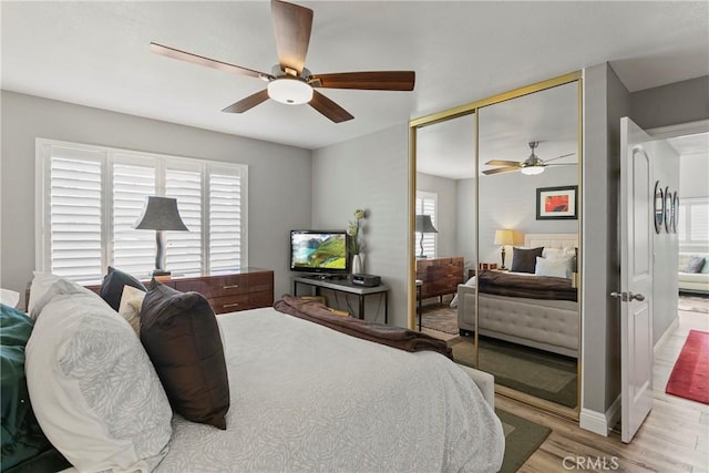 bedroom featuring ceiling fan, light hardwood / wood-style flooring, and a closet